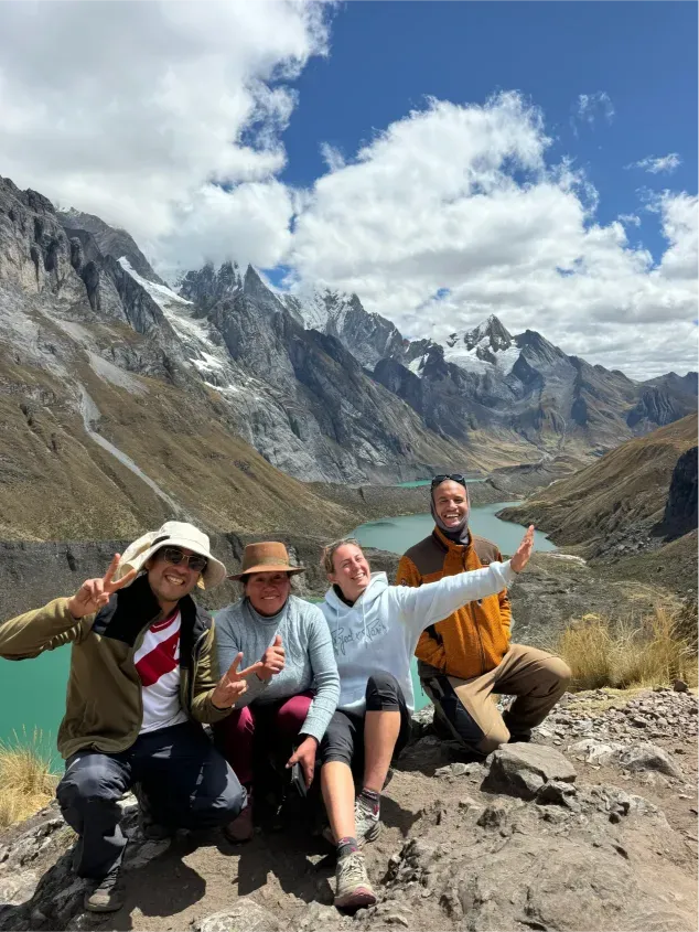 Smiling trekkers resting above a turquoise lake