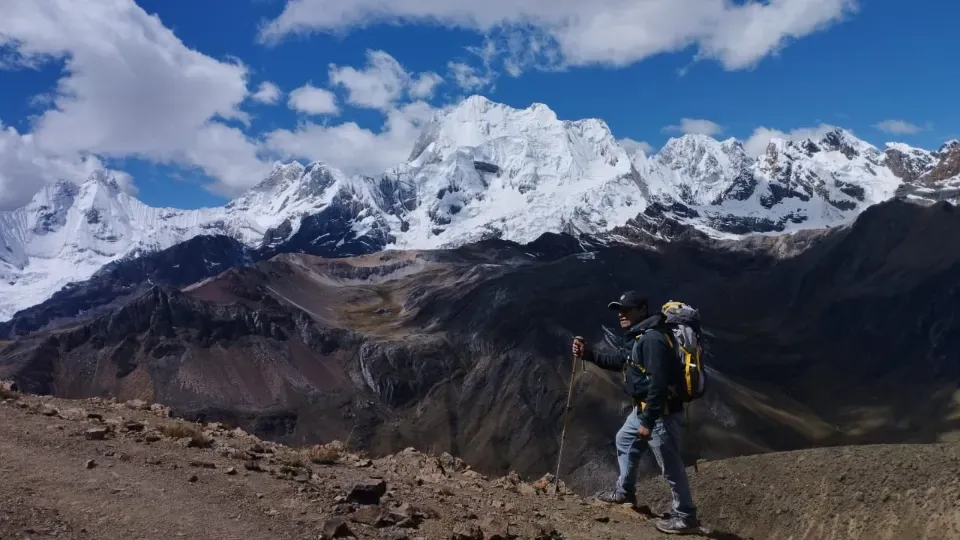 A trekker looking out at a long line of glaciated peaks